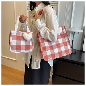 Detail of red and white checkered canvas tote bags with heart plush charm and metal clasp