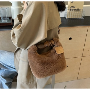 Close-up of brown plush handbag with pleated PU handle and gold hardware detail
