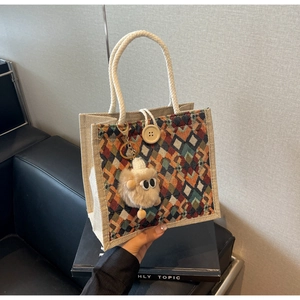 Close-up of geometric linen tote bag with woven rope handle and plush monster charm