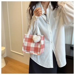 Detail of red gingham mini tote bag with white heart plush pendant and webbing handle