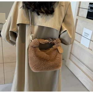 Close-up of fluffy brown plush tote with ruched leather handle and golden metal hooks