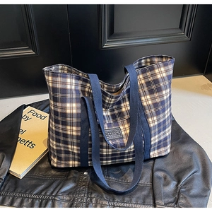 Détail du sac cabas à carreaux avec sangles tissées et étiquette mode sur cuir