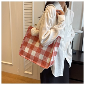 Detail of red and white checkered tote bag with a white plush heart charm on the strap