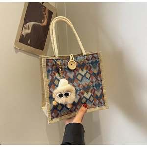 Detail of waterproof linen tote bag with colorful geometric patterns and fuzzy monster charm