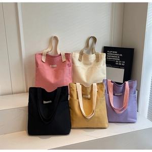 Five canvas tote bags in various colors displayed on white steps for daily fashion use