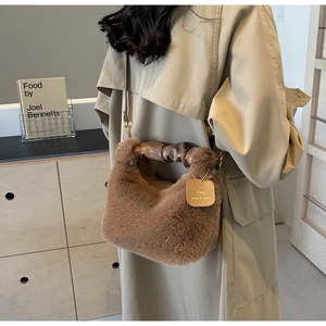 Macro detail of plush brown faux fur handbag with ruched leather handle and gold charm