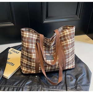 Détail d'un grand sac cabas à carreaux marron avec des anses larges et étiquette