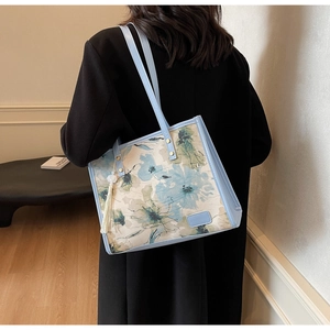 Détail du grand sac cabas fleuri avec bordure en cuir bleu et pompon décoratif