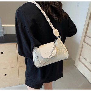 Close-up of beige baguette bag with floral embroidery and decorative metal flower chain