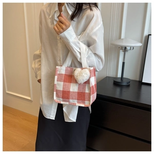 Detail of red checkerboard tote bag with heart charm shown in a minimalist interior