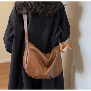 Detail of dark brown retro crescent bag with wide strap and cute toast pendant charm
