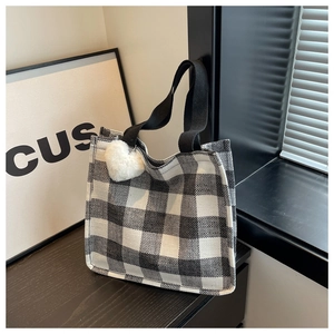 Detail of checkered tote bag with black strap and white heart plush keychain charm