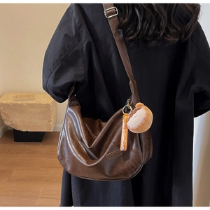 Detail of a brown vintage hobo bag with teddy bear charm and stylish shoulder strap