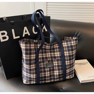 Détail d'un sac cabas à carreaux bleu et beige avec étiquette FASHION sur canapé