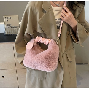 Close-up of pink faux fur handbag featuring pleated leather handles and detachable strap