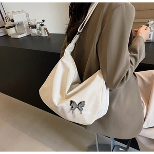 Détail du sac à bandoulière blanc plissé avec ornement papillon en métal argenté