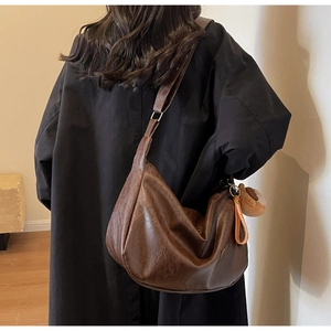 Detail of dark brown lychee leather hobo bag with plush charm on wide shoulder strap
