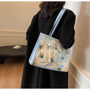 Détail d'un sac cabas floral bleu clair avec pompon élégant et finitions en cuir souple