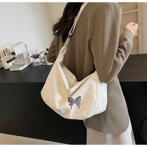 Détail d'un sac cabas plissé blanc avec boucle papillon argentée et large bandoulière