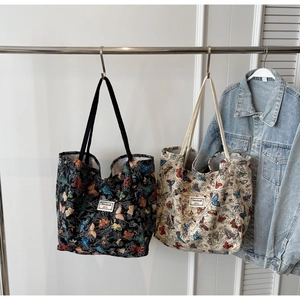 Detail of canvas tote bags with colorful butterfly prints in black and beige finishes
