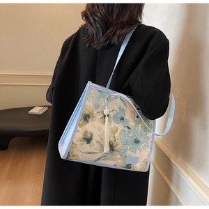 Vue latérale du grand cabas à fleurs bleu clair avec breloque à franges sur modèle