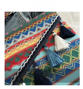 Détail d'un sac bohème tissé avec motifs géométriques colorés et pompons à franges