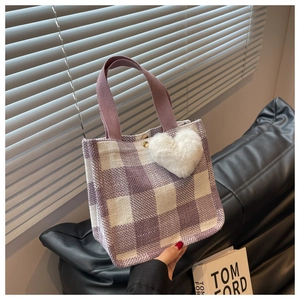 Detail of purple plaid tote bag with woven handles and a cute plush heart charm