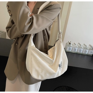 Détail du sac bandoulière blanc demi-lune avec breloque papillon et texture cuir raffinée