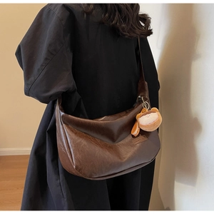 Detail of vintage brown leather hobo bag with fashion label and plush charm on the strap