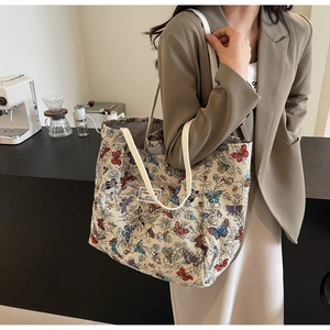 Detail of a butterfly print canvas tote bag featuring white cotton shoulder straps