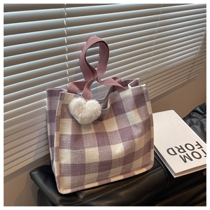 Detail of purple and beige checkered tote bag with heart charm and woven handles
