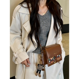 Brown flap crossbody bag with geometric fabric panel and cute bear charm shown on model