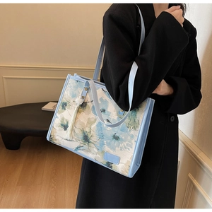 Détail d'un grand cabas floral français avec pompons bleus sur un manteau noir
