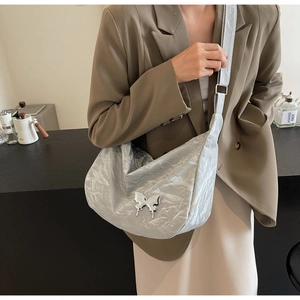 Détail du sac croissant argenté avec texture plissée métallique et boucle papillon