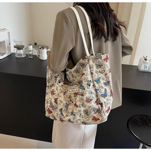 Detailed back view of a canvas tote bag with colorful butterfly patterns and logo label