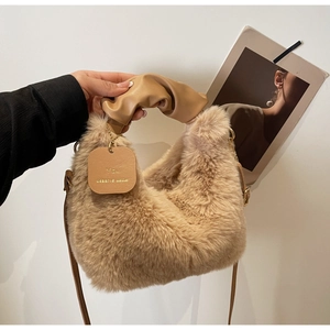 Close-up of beige plush handbag with pleated leather cloud handle and text charm