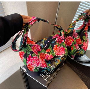 Detail of floral pattern hobo bag with vibrant phoenix and peony prints on black fabric