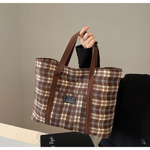 Détail d'un grand sac cabas à carreaux avec anses marron et étiquette de mode