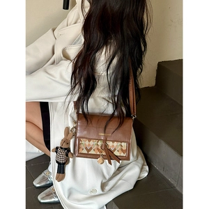 Detail of vintage brown crossbody bag featuring woven pattern and a cute bunny pendant