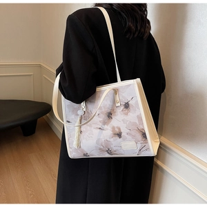 Détail du sac cabas à imprimé floral avec bordure en cuir crème et pompon décoratif élégant