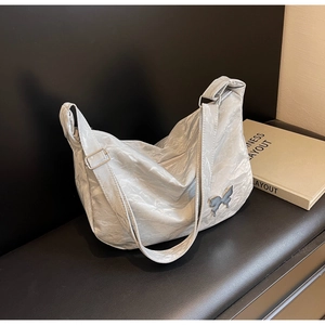 Détail de la texture plissée argentée et du logo papillon bleu sur le sac à bandoulière