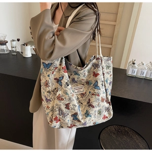 Side view of large canvas tote bag with colorful butterfly prints on a female model