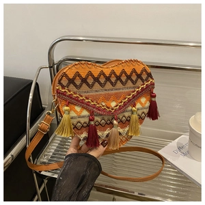 Detail of heart-shaped ethnic woven bag with colorful fringes and leather strap