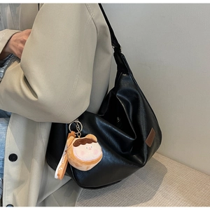 Detail of black faux leather hobo bag featuring natural texture and a sweet plush charm