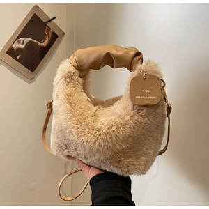 Detail of camel faux fur handbag showing pleated leather handle and gold lettering tag