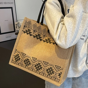 Large woven jute tote bag with ethnic geometric patterns shown on a model for daily use