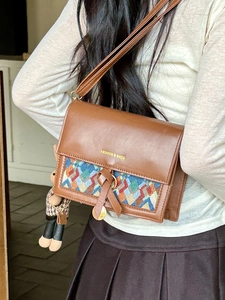 Detail of retro brown crossbody bag with woven pattern and cute rabbit charm accessory