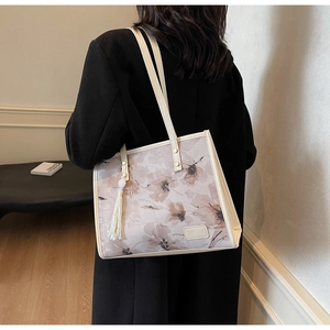Détail du cabas floral montrant des motifs élégants et un délicat pompon blanc à franges