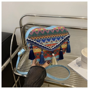 Macro view of bohemian heart-shaped woven bag with embroidery and fringe detail