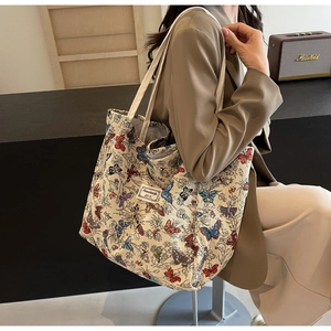 Detailed macro view of large canvas tote bag featuring colorful butterfly prints and brand label